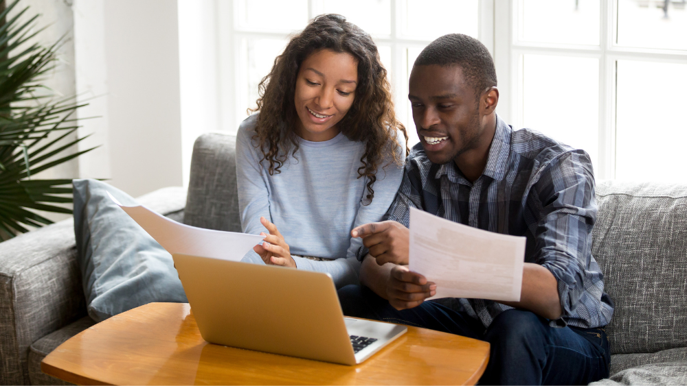 Young Couple Smiling And Looking At Their Finances